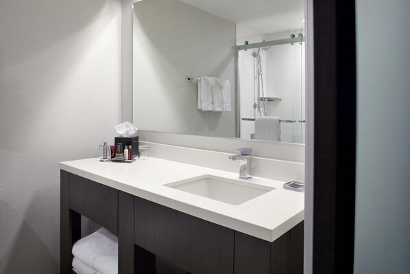 A modern bathroom with a white sink, a large mirror, and a shower visible in the reflection. - Marriott Hartford/Windsor Airport (Windsor)