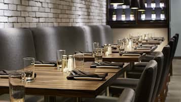 Un restaurante con mesas de madera largas, sillas negras e iluminación colgante.