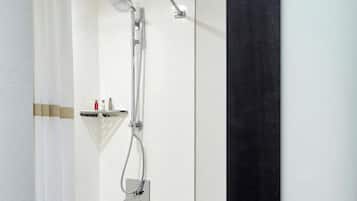 A modern bathroom with a bathtub, shower, and a shelf with toiletries.