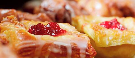 A close-up of pastries with a glossy glaze and a red topping.
