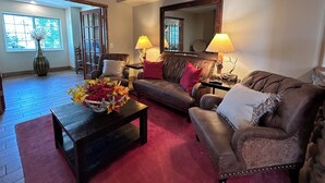 A living room with a brown leather sofa, a coffee table with a vase of flowers, and two lamps on side tables. - Microtel Inn & Suites by Wyndham Bozeman (Bozeman)