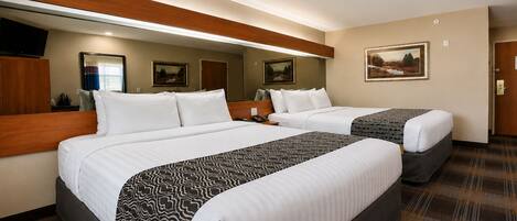 A hotel room with two beds, a television, a painting, and a door.