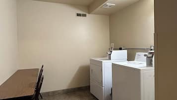A compact kitchen with a dining table and chairs, a washer and dryer, and a small window.
