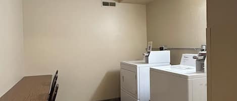 Una cocina compacta con una mesa y sillas, lavadora y secadora, y un ventanal.
