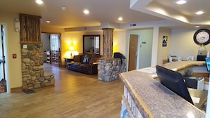 A spacious lobby with a stone pillar, a reception desk, a leather sofa, and a wooden floor. - Microtel Inn & Suites by Wyndham Bozeman (Bozeman)