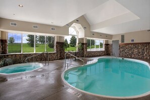 An indoor swimming pool with a stone wall, a large window, and a view of the outdoors. - Microtel Inn & Suites by Wyndham Bozeman (Bozeman)