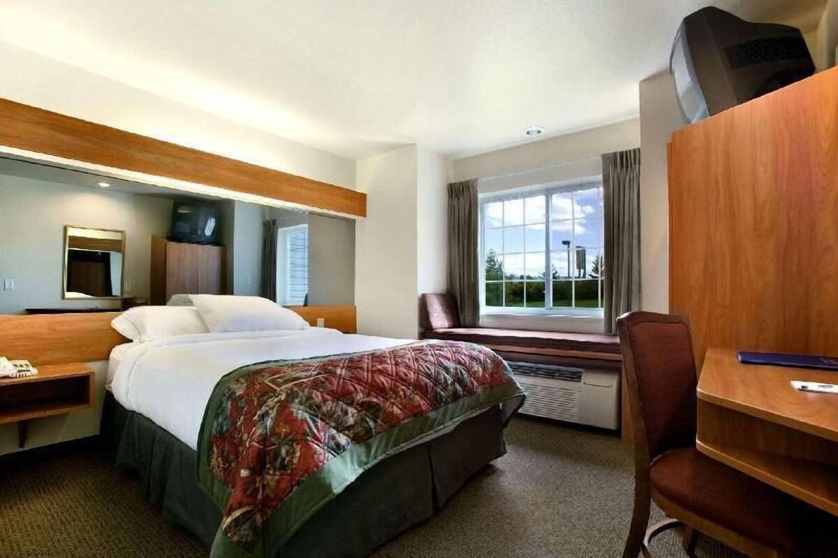 Une chambre d’hôtel comprenant un lit, un bureau, une chaise, une fenêtre avec vue, un miroir et un téléviseur.