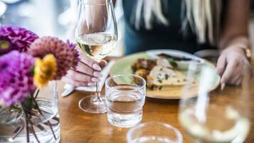 A dining table with a glass of white wine, a glass of water, and a plate of food.