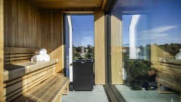 Uma sala de sauna com bancos de madeira e unidade sauna preta.