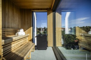 Uma sala de sauna com bancos de madeira e unidade sauna preta.