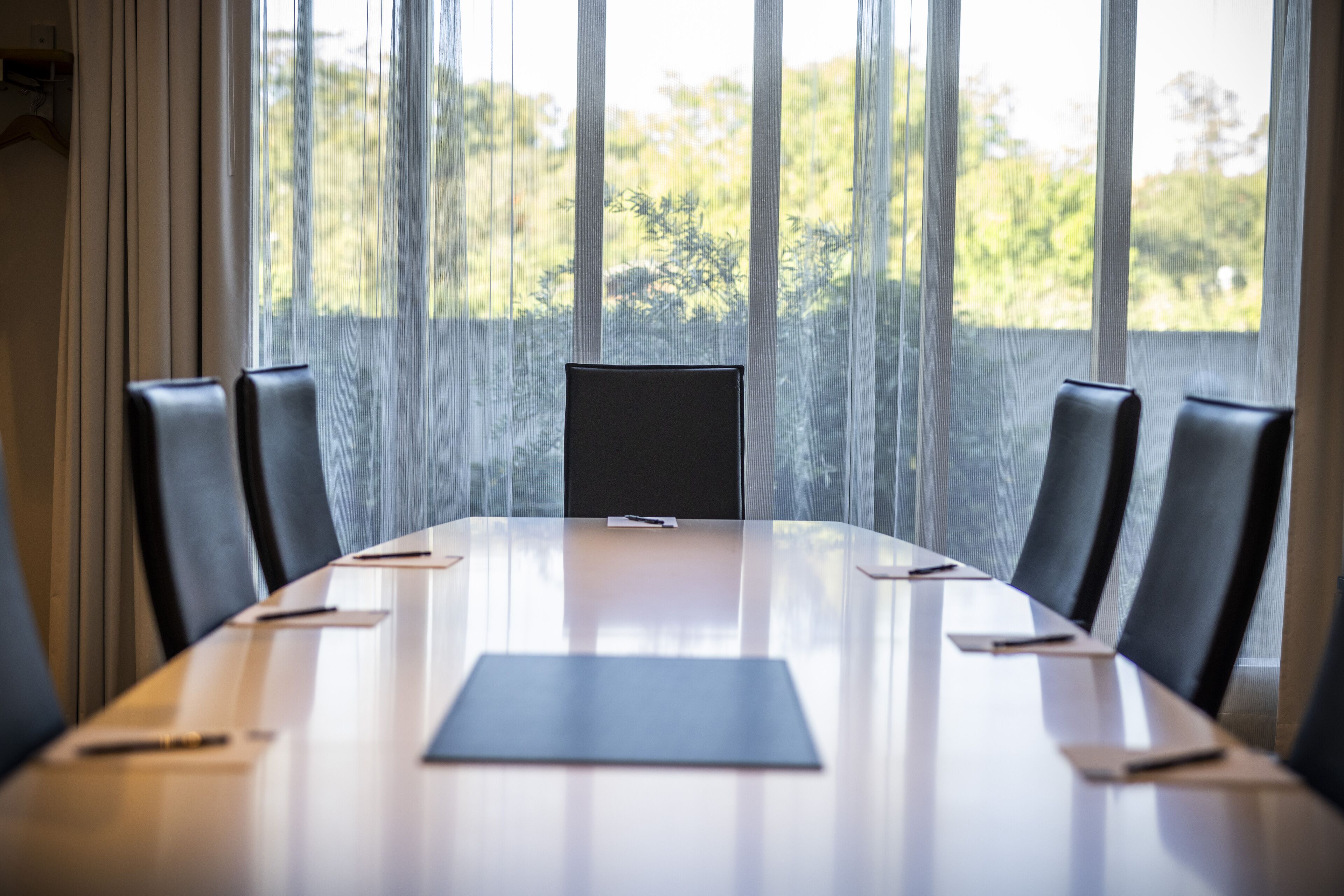 A conference room with a long table, chairs, and a projector screen.