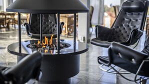 Un espacio lounge moderno con una chimenea central, sillones de cuero negro y una distribución amplia.