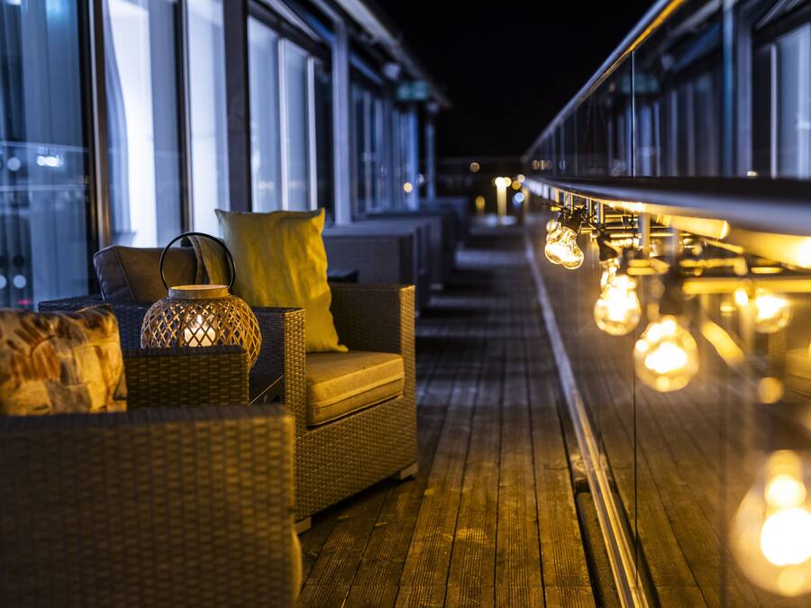 A wooden deck with wicker furniture and hanging lights.