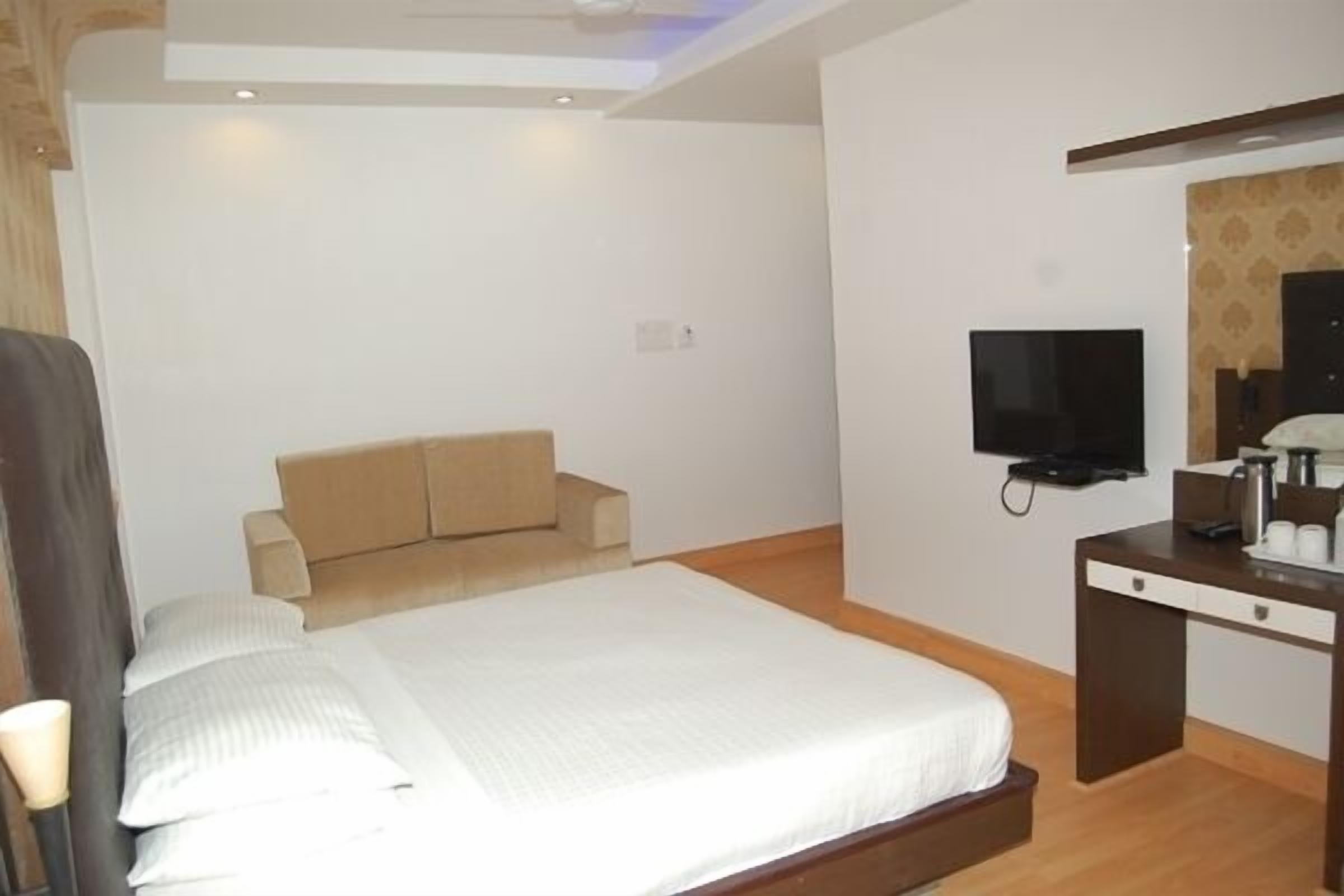 A hotel room with a bed, a TV, a desk, and a sofa.