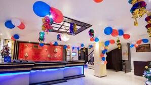 A reception area with a red wall, a reception desk, and a chandelier. - Hotel Surya International (New Delhi)
