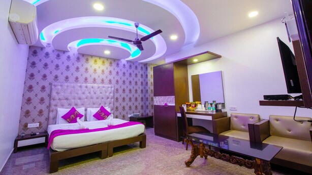 A modern hotel room with a bed, a desk, a sofa, and a ceiling fan. - Hotel Surya International (New Delhi)