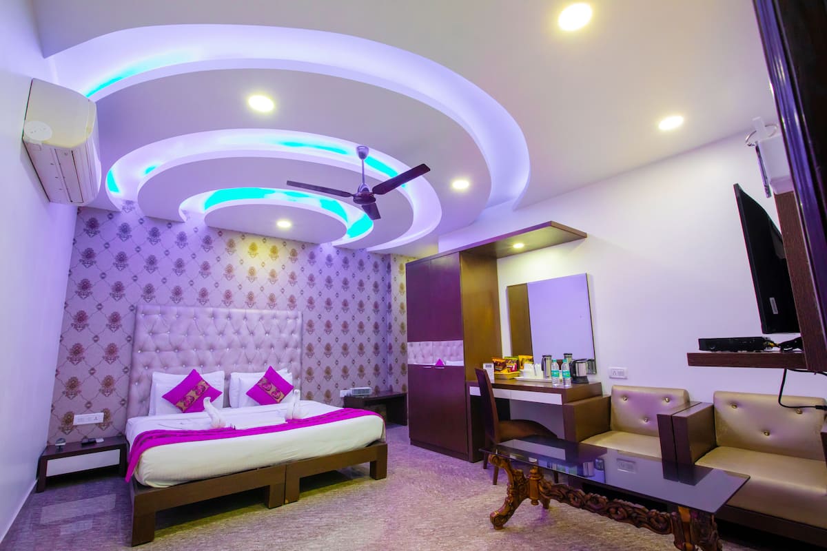 Una habitación de hotel moderna con cama, escritorio, sofá y ventilador de techo.
