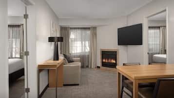 Une chambre d’hôtel équipée d’un lit, d’un canapé, d’une télévision, d’une cheminée et d’une table à manger.