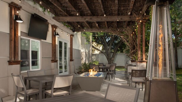 An outdoor patio with a fire feature, seating, and a pergola with string lights. - Residence Inn Marriott Palo Alto Los Altos (Los Altos)