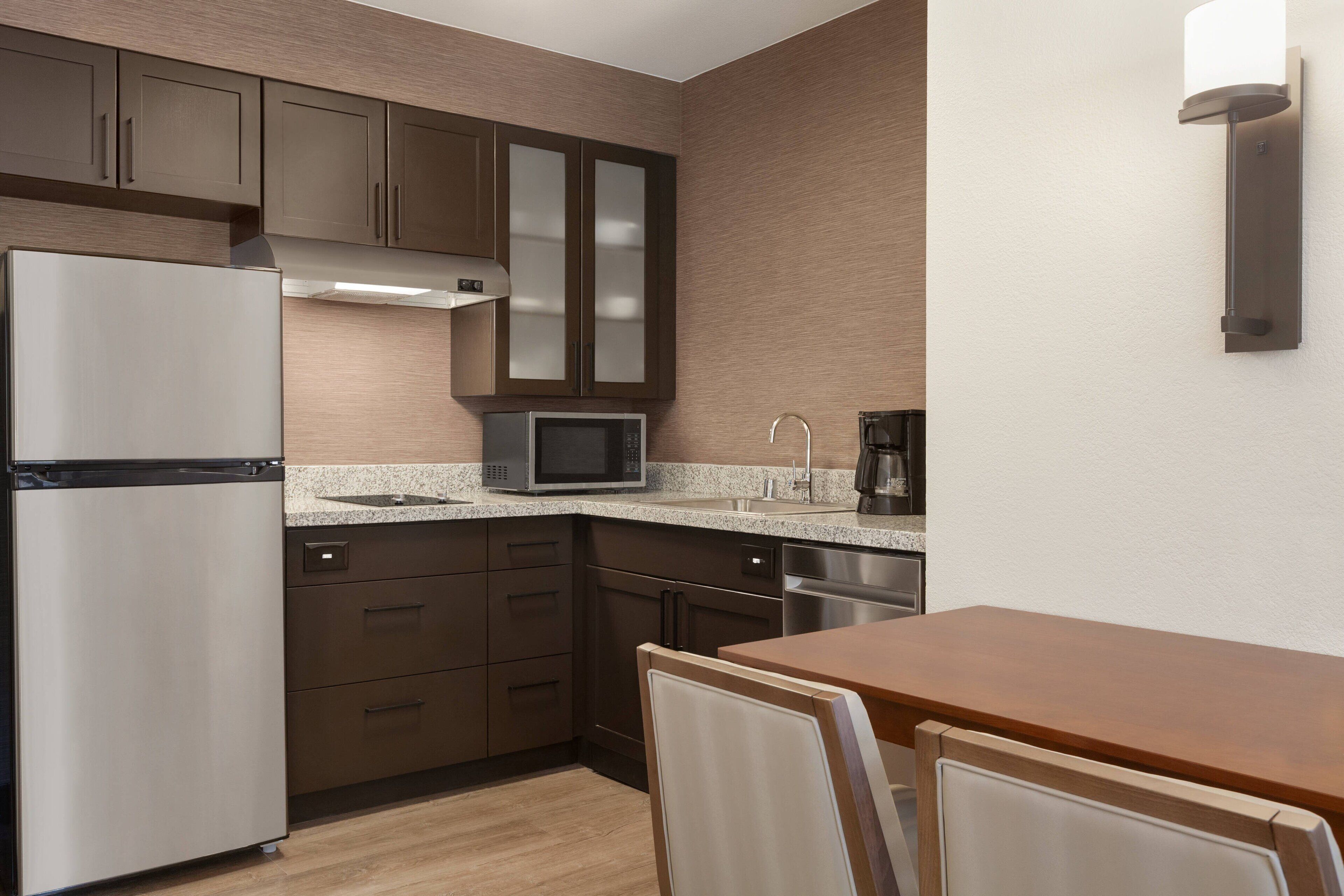 A modern kitchen with a refrigerator, microwave, and coffee maker.
