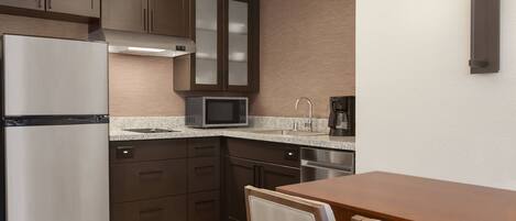 A modern kitchen with a refrigerator, microwave, and coffee maker.