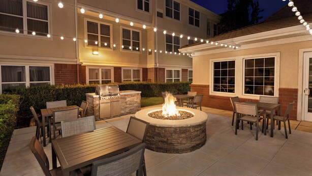 An outdoor patio area with a fire pit, seating, and string lights. - Residence Inn by Marriott San Jose South\/Morgan Hill (Morgan Hill)