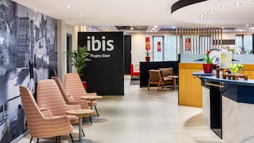 A hotel lobby with seating, a reception desk, and a mural on the wall.