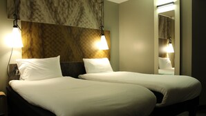Habitación de hotel con dos camas, una pared de mármol y dos lámparas de noche.