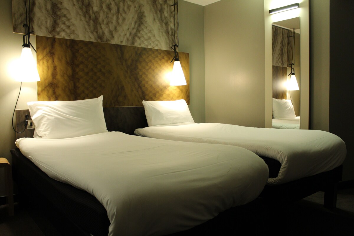 A hotel room with two beds, a marble wall, and two bedside lamps.