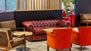 Un área de estar moderna con sofá de cuero, mesa de centro de madera y sillas color naranja vibrante.