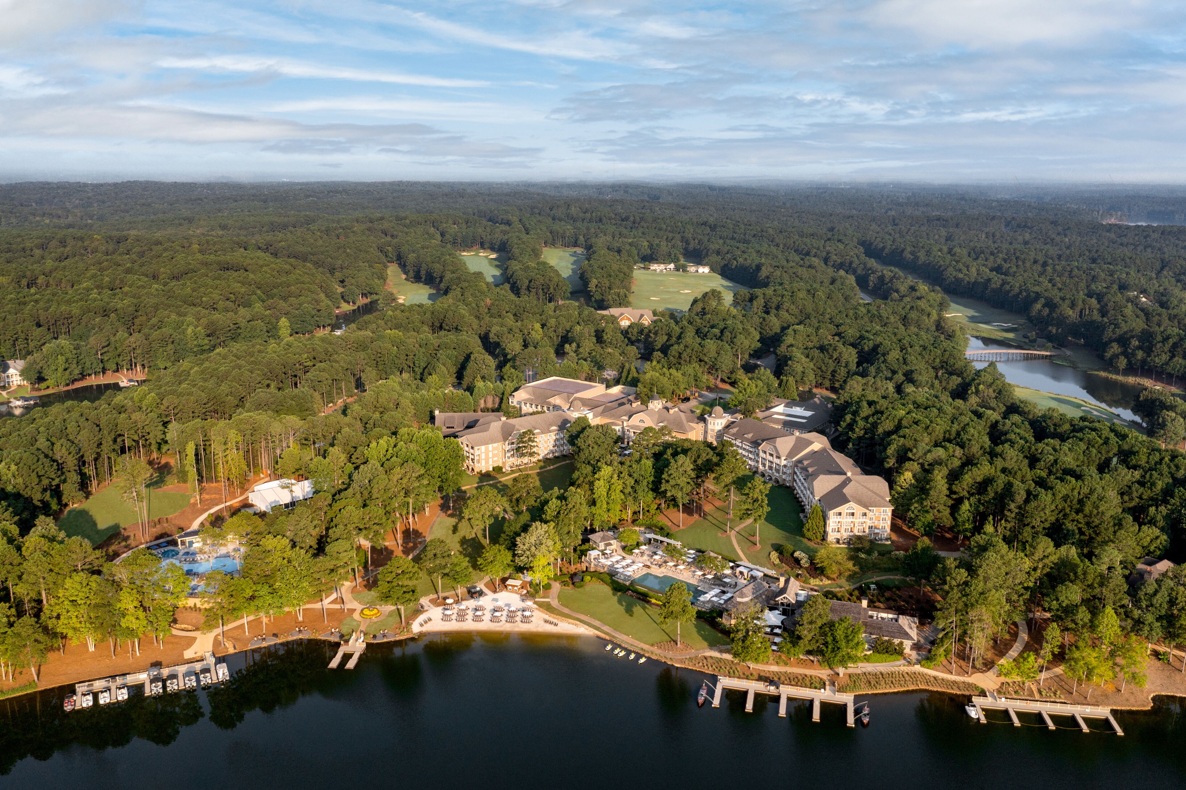 An aerial view of a resort with multiple buildings, a lake, and a golf course.