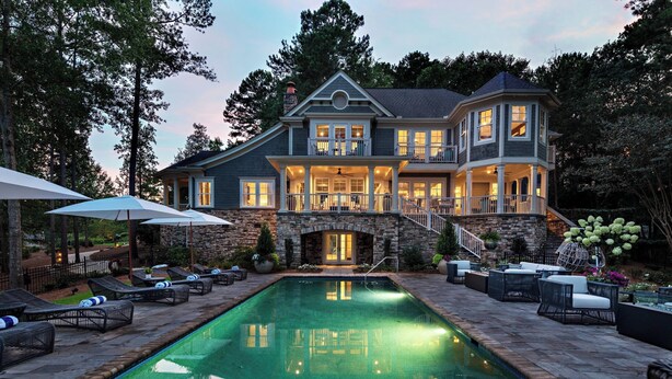 Une grande maison dotée d’une piscine, d’un espace extérieur aménagé et d’une façade en pierre.