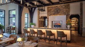 Un restaurant moderne doté d’une cheminée en pierre, d’un bar et de chaises en osier.