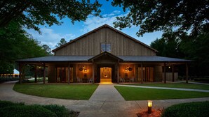 Un grand bâtiment en bois, de style grange, doté d’un porche couvert et d’une entrée centrale.