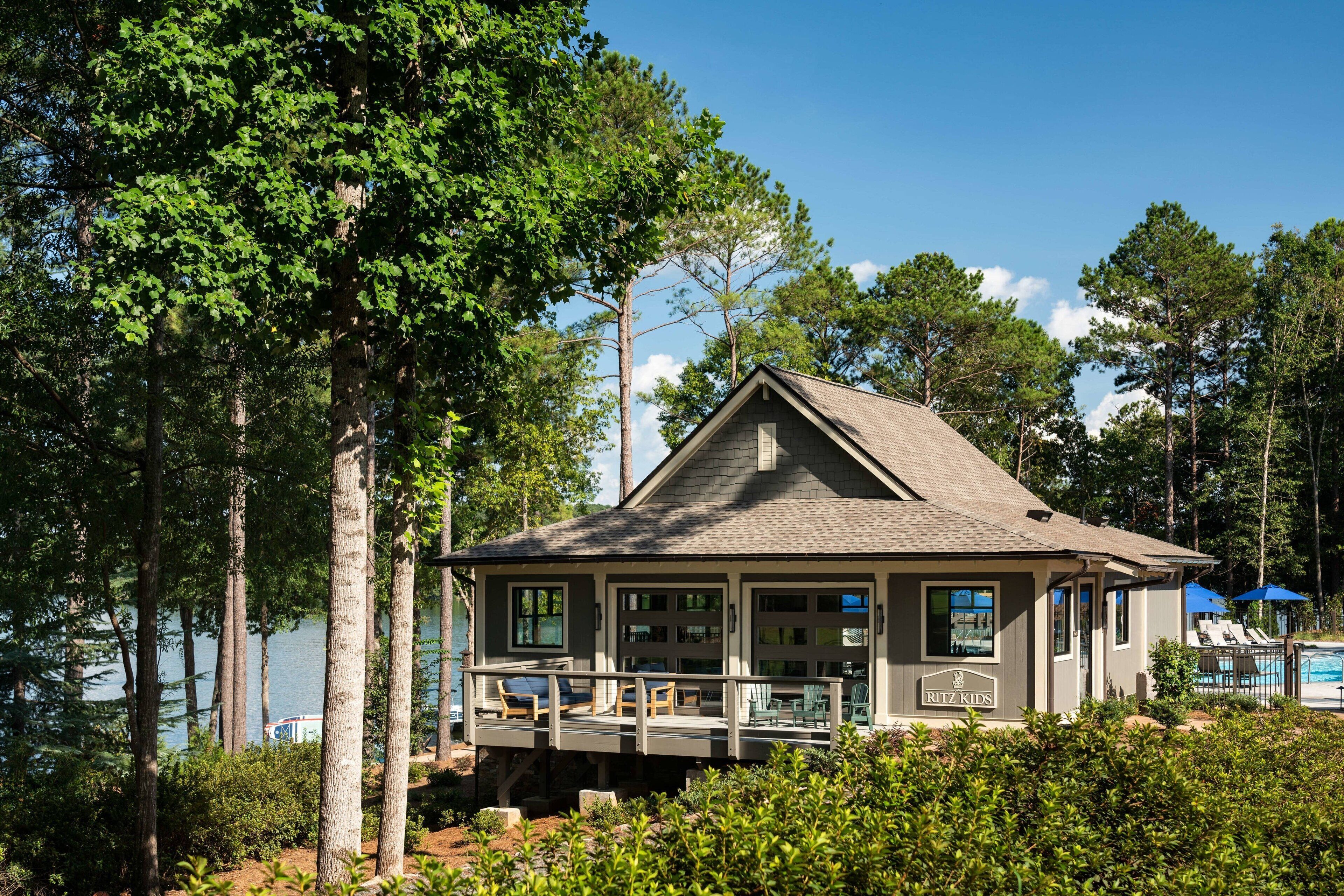 A lodge with a deck overlooking a lake, surrounded by trees.