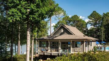 A lodge with a deck overlooking a lake, surrounded by trees.