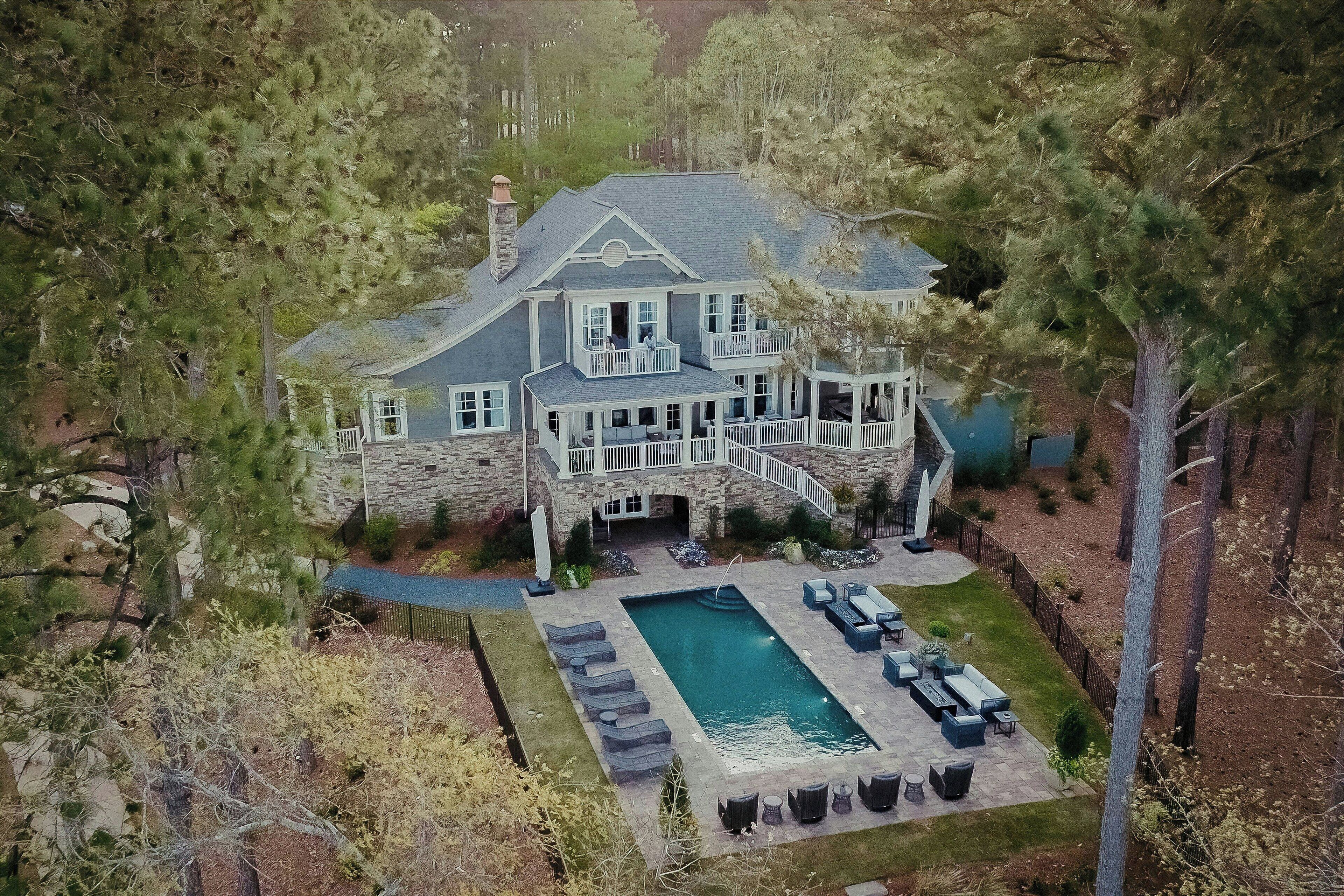 Une grande maison en pierre dotée d’une piscine, d’un espace extérieur aménagé et d’un escalier en pierre menant à l’entrée.