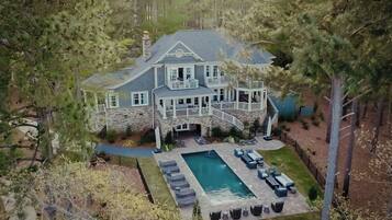 A large stone house with a swimming pool, outdoor seating, and a stone staircase leading to the entrance.
