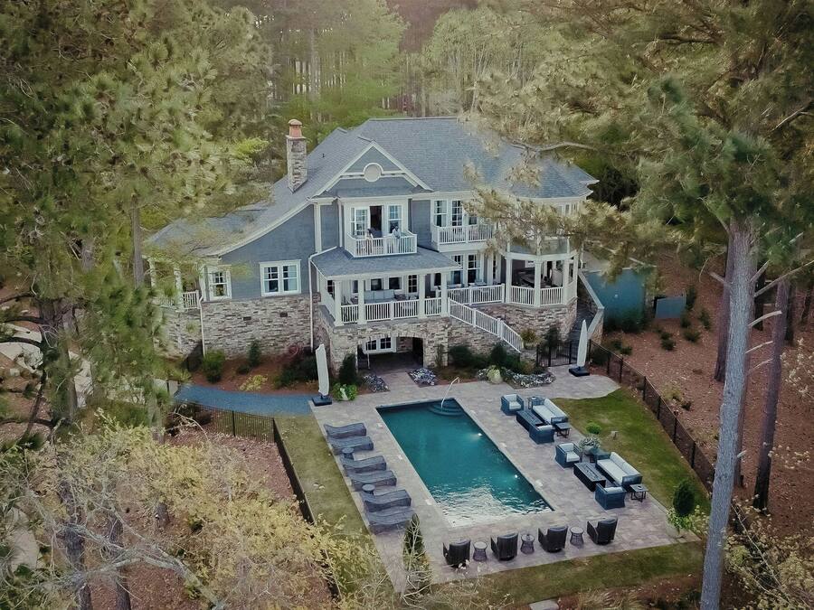 A large stone house with a swimming pool, outdoor seating, and a stone staircase leading to the entrance.