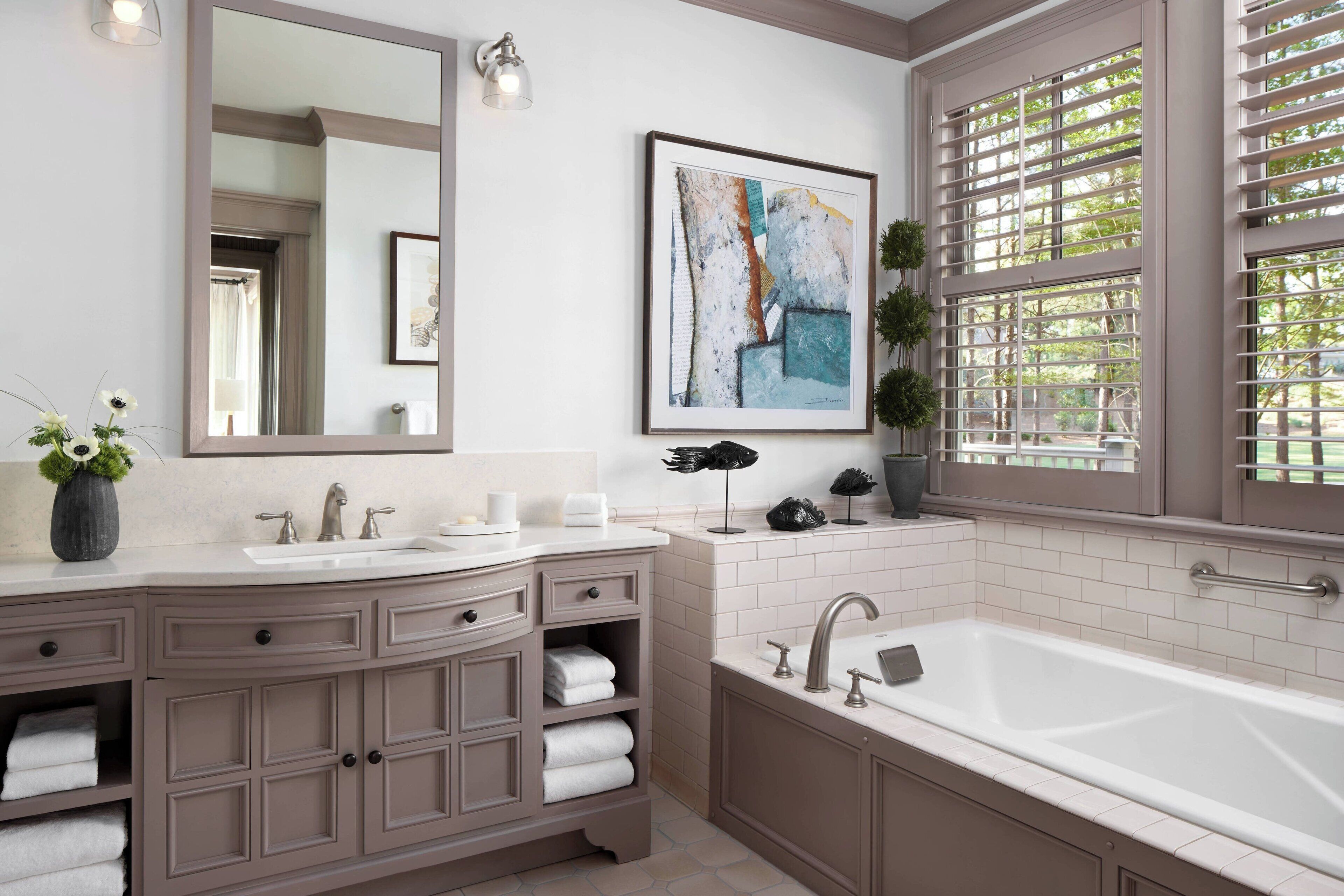 Une salle de bain moderne avec un grand miroir, deux lavabos, une baignoire et une fenêtre équipée de stores.