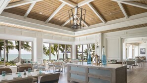 Un comedor amplio con una isla grande, muebles blancos y vistas al océano.