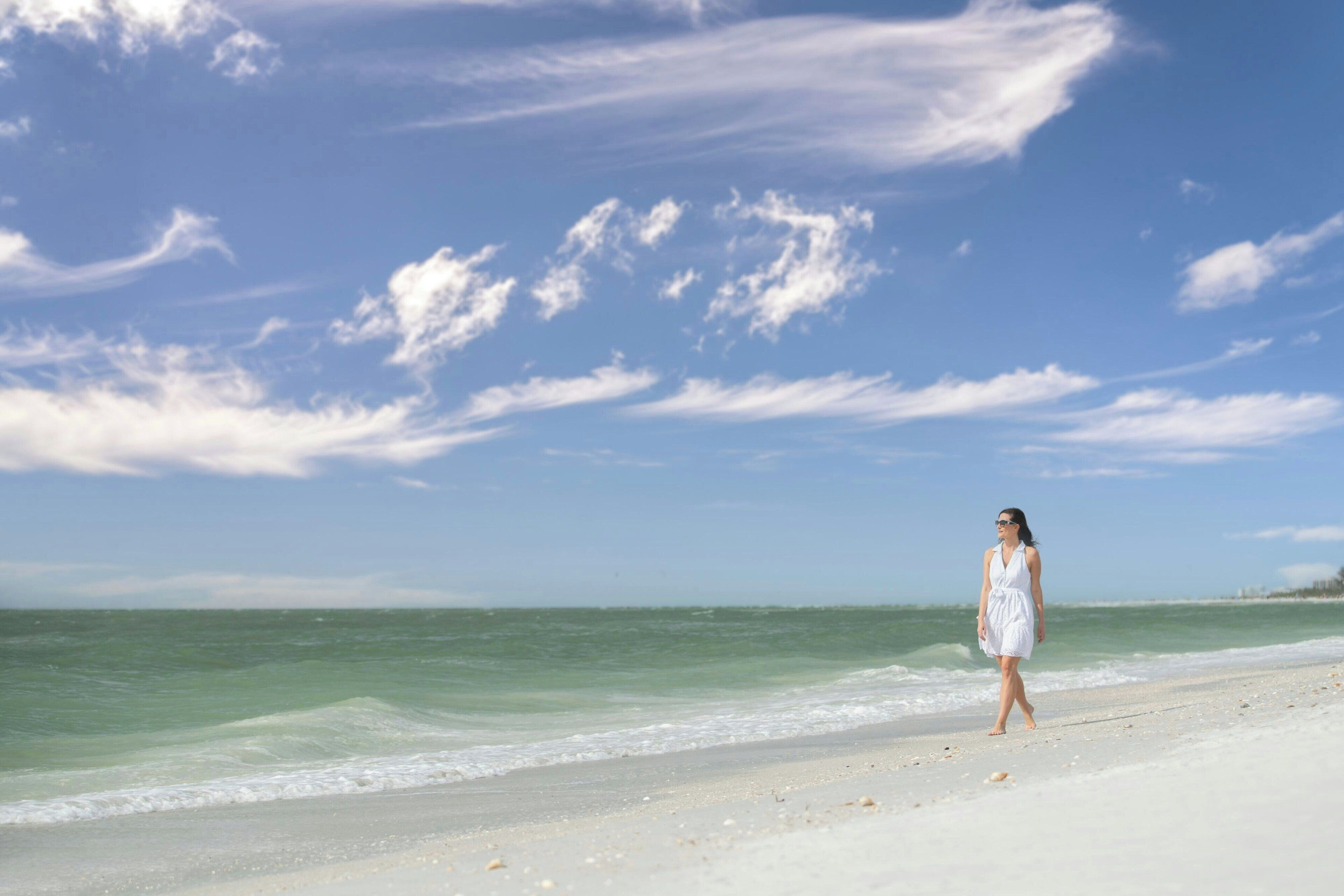 A beach with a person walking along the shore.