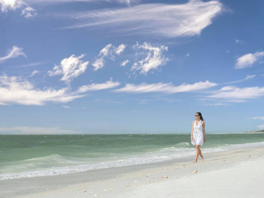 A beach with a person walking along the shore.