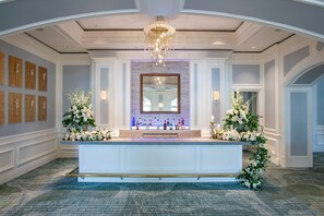 A reception area with a white reception desk, a large mirror above it, and a chandelier.