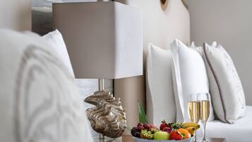 Una habitación elegante con una lámpara moderna, una concha decorativa, un frutero y dos copas de champán sobre una mesa de madera.
