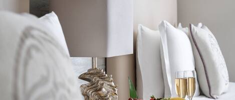 Una habitación elegante con una lámpara moderna, una concha decorativa, un frutero y dos copas de champán sobre una mesa de madera.