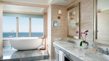 Un baño moderno con una bañera independiente, dos lavamanos y un espejo grande.