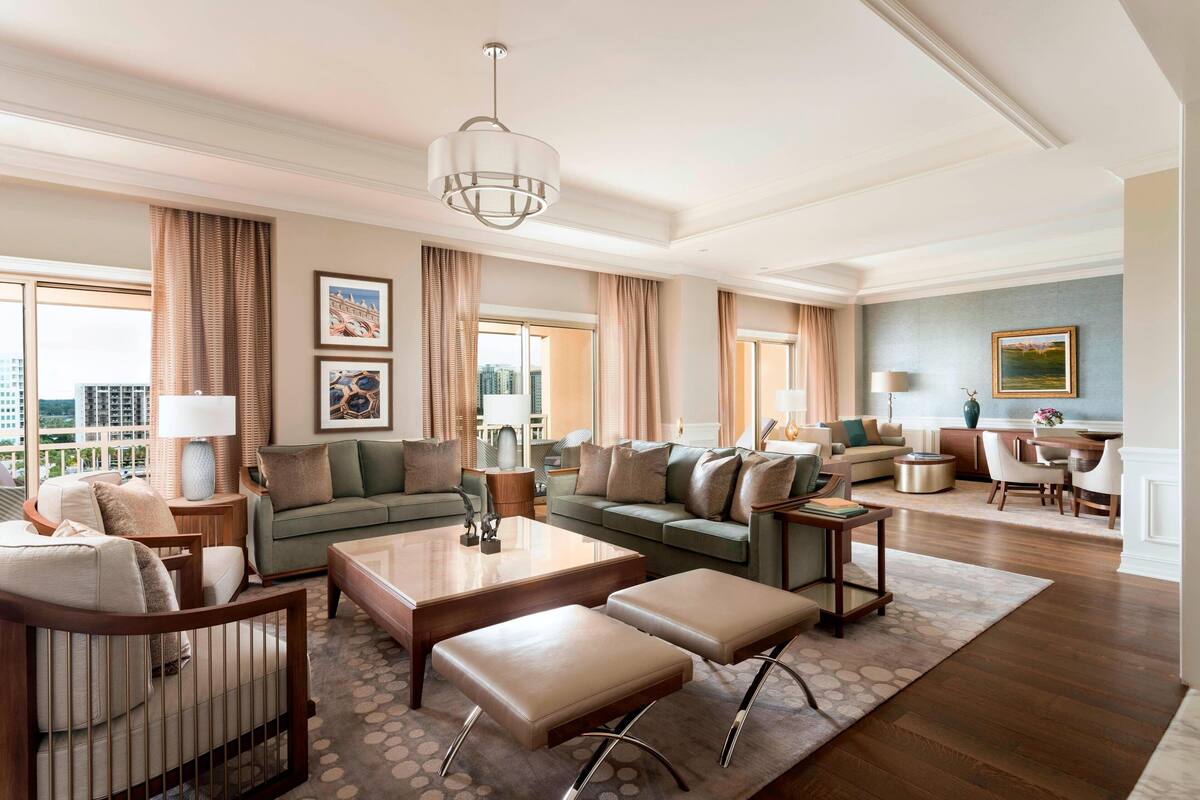 A spacious living room with a large sofa, a coffee table, and a dining area with a table and chairs.