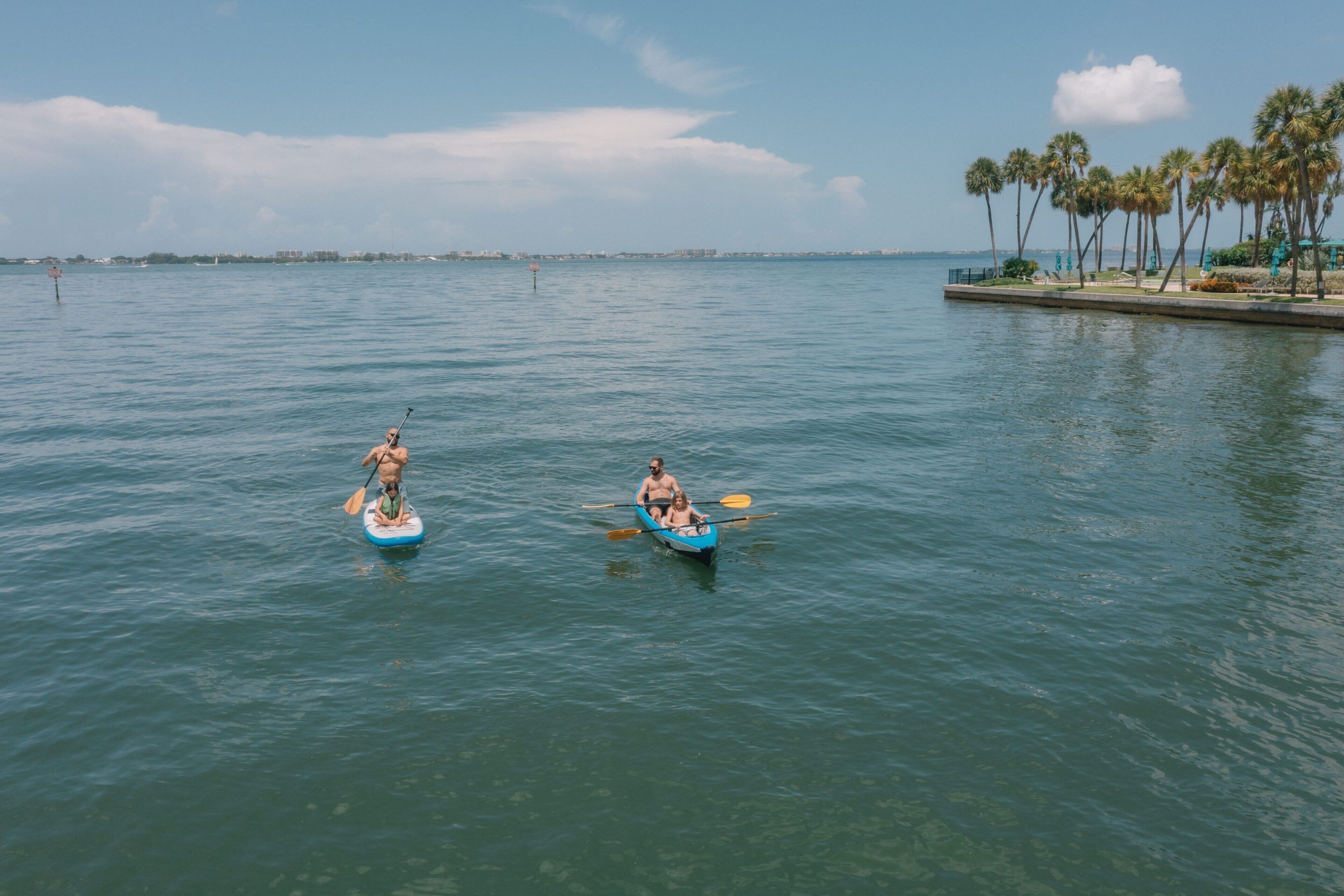 Dos personas remando en un canoa azul sobre aguas tranquilas.