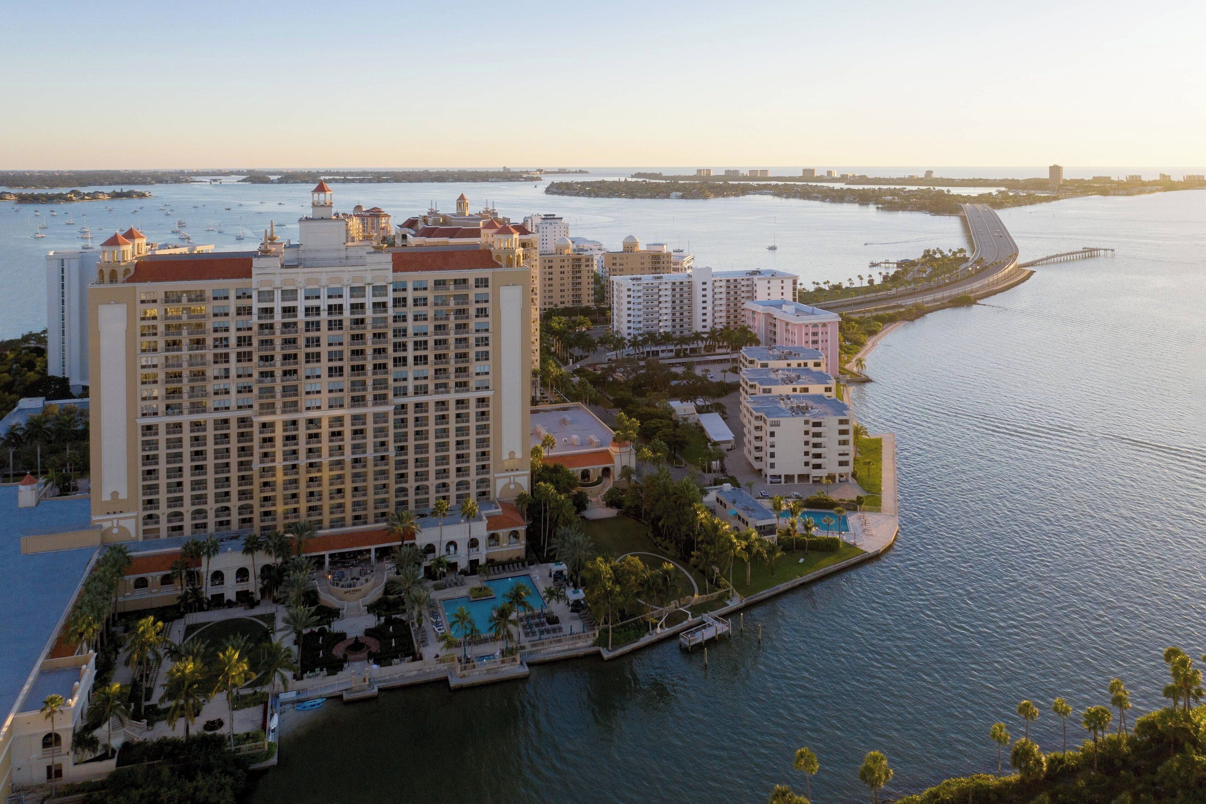 A high-rise hotel with multiple balconies, a pool area, and a marina.